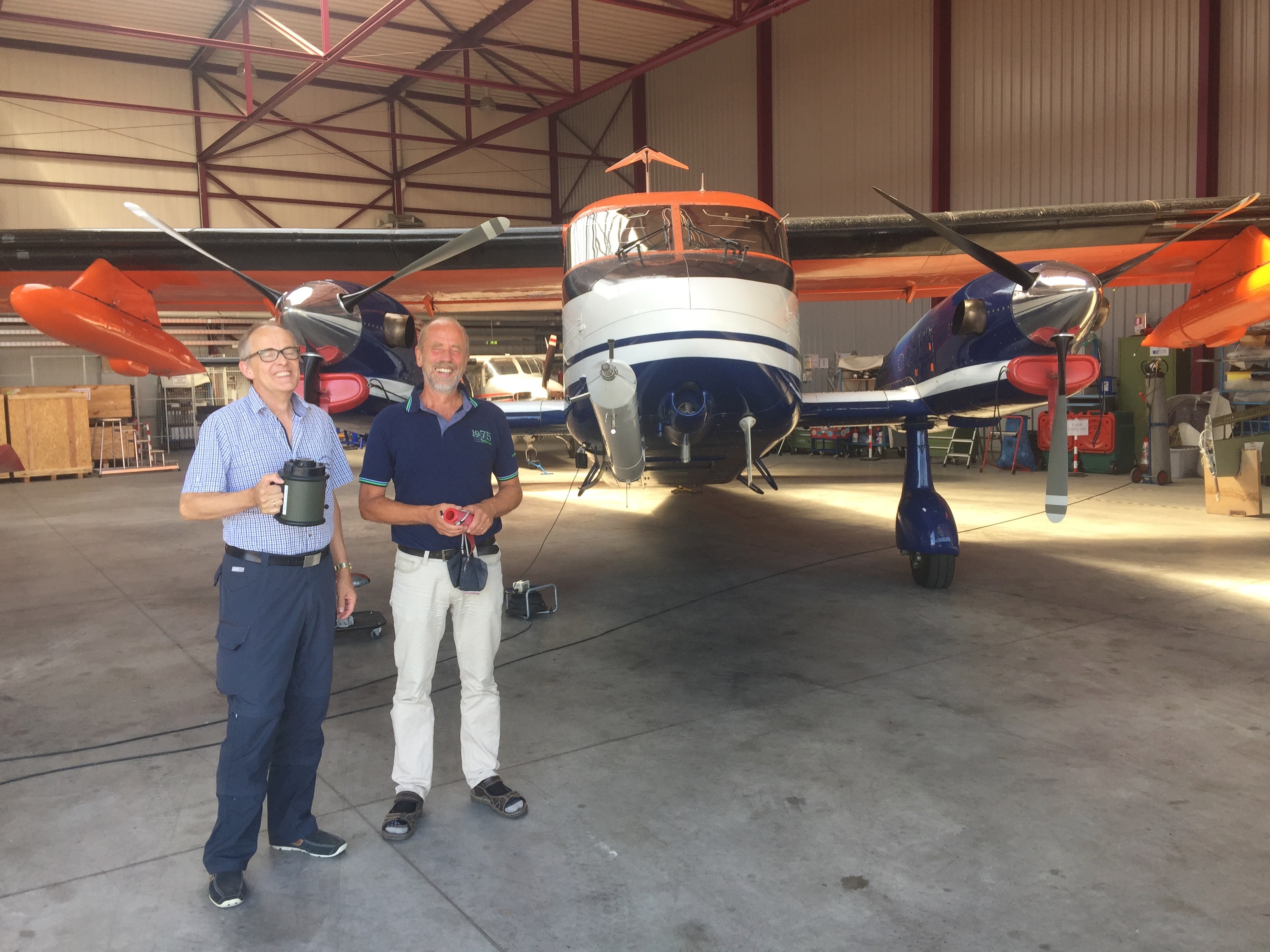 Two researchers stand inside the hanger of the Dornier DO-128. One is holding a SASS® 3100 air sampler in their hand.